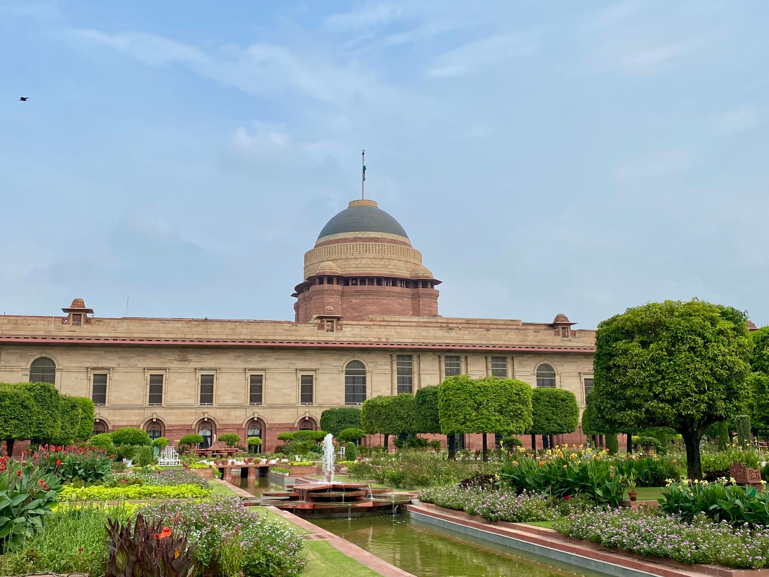 Indian institutional secretariat with sandstone architecture, Rashtrapati Bhavan dome, Indian national flag and formal lawns